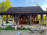 cabane avec lgrande table et mobilier de lounge, barbecue et foyer de feu.